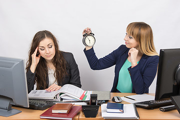 Image showing  In the office at the end of the working day is one staff member would look at the clock and the other continues to work