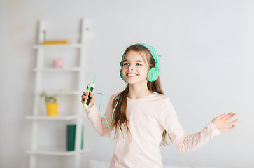 Image showing girl jumping on bed with smartphone and headphones