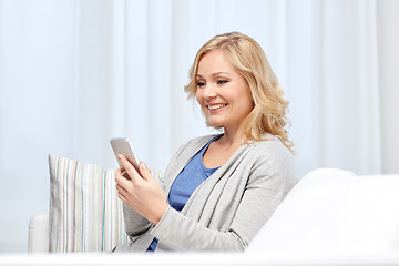 Image showing smiling woman with smartphone texting at home