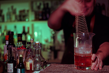 Image showing Bartender nixed cocktail in glass cup.