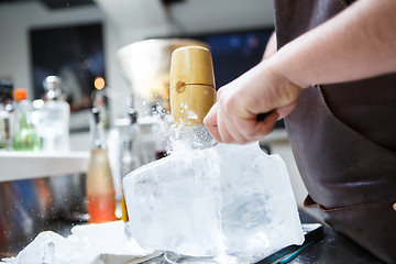 Image showing Bartender mannually crushed ice with wooden hammer and metal knife.