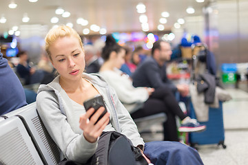 Image showing Female traveler using cell phone while waiting.
