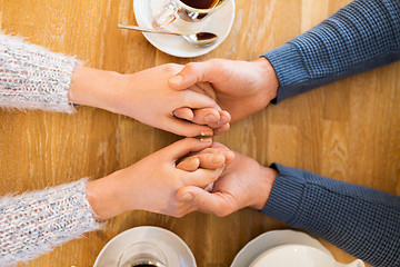 Image showing close up of couple holding hands at restaurant