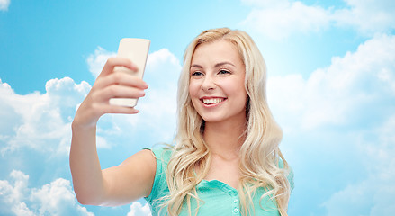 Image showing smiling young woman taking selfie with smartphone