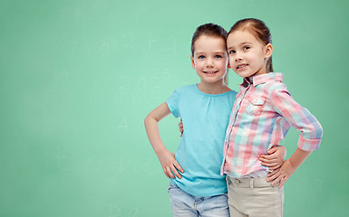 Image showing smiling girls hugging over green school board