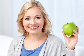 Image showing happy middle aged woman with green apple at home