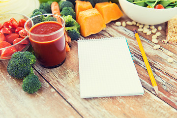 Image showing close up of ripe vegetables and notebook on table