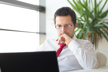 Image showing Businessman in office reading on laptop computer.