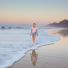 Image showing Lady walking on sandy beach in sunset.