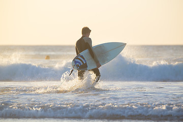 Image showing Silhouette of surfer on beach with surfboard.