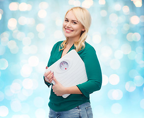 Image showing smiling young woman holding scales