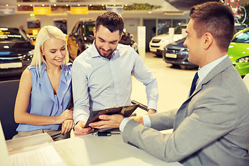 Image showing happy couple with car dealer in auto show or salon