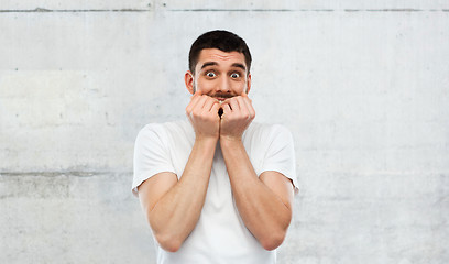 Image showing scared man in white t-shirt over gray wall