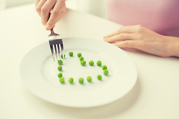 Image showing close up of woman with fork eating peas