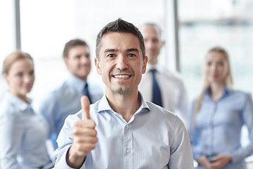 Image showing smiling business team showing thumbs up in office