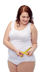 Image showing happy young plus size woman with measuring tape