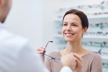 Image showing woman taking glasses from optician at optics store