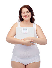 Image showing happy young plus size woman holding scales