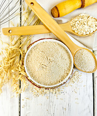 Image showing Flour oat in white bowl with bran and flakes on light board