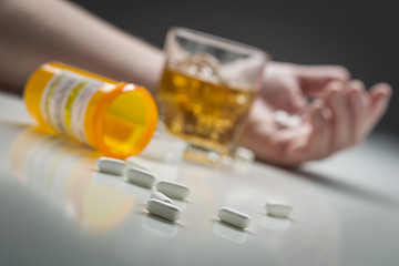 Image showing Hand on Ground Behind Scattered Drugs and Glass of Alcohol