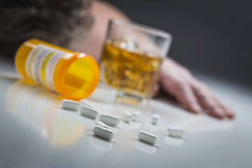 Image showing Passed Out Man Behind Scattered Drugs and Glass of Alcohol