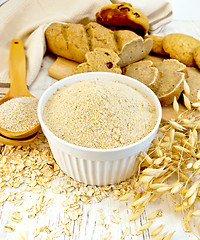 Image showing Flour oat in white bowl with bran in spoon on board