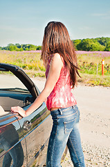 Image showing Young brunette female standing near car