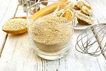 Image showing Flour sesame in glassful with spoon on board
