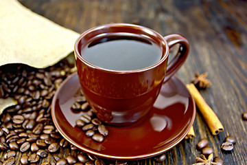 Image showing Coffee in brown cup with cinnamon and bag on board