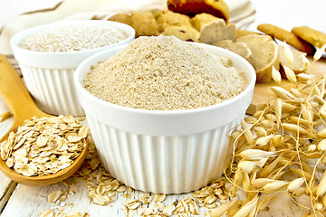 Image showing Flour oat in white bowl with flakes in spoon on board