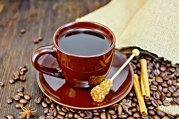 Image showing Coffee in brown cup with sugar and bag on board