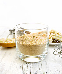 Image showing Flour sesame in glassful on board