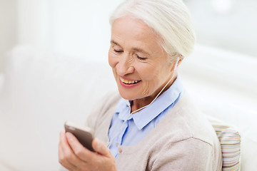 Image showing senior woman with smartphone and earphones at home