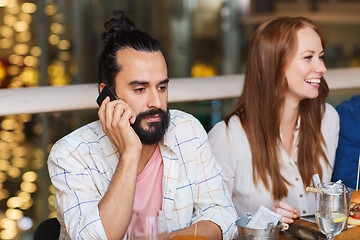 Image showing man with smartphone and friends at restaurant