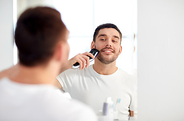 Image showing man shaving beard with trimmer at bathroom