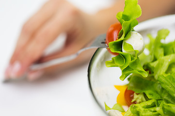 Image showing close up of young woman eating salad at home