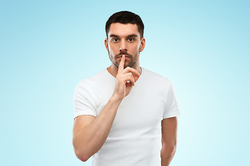 Image showing young man making hush sign over blue background