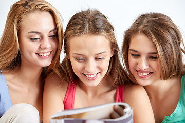 Image showing friends or teen girls reading magazine at home