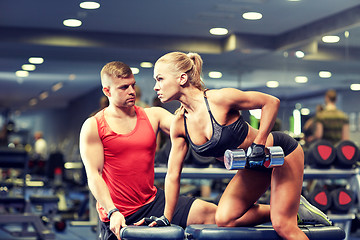 Image showing young couple with dumbbell flexing muscles in gym