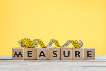 Image showing Measure tape on a wooden sign