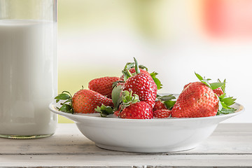 Image showing Strawberries on a plate with a bottle of milk