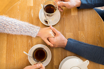 Image showing close up of couple holding hands at restaurant