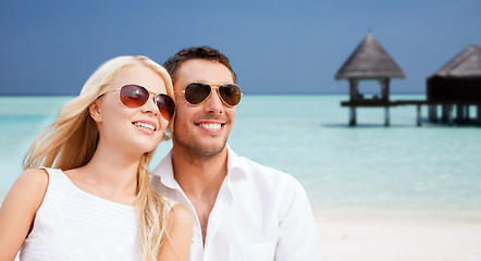 Image showing happy couple in shades over beach with bungalow