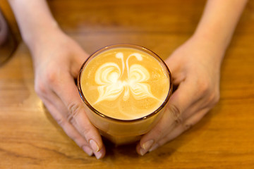 Image showing close up of hands with latte art in coffee cup