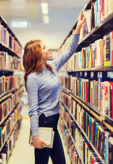 Image showing happy student girl or woman with book in library