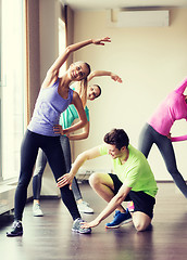 Image showing group of smiling people stretching in gym