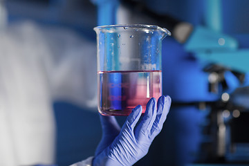 Image showing close up of hand holding glass in chemical lab