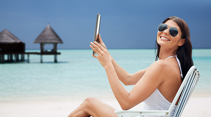 Image showing smiling woman with tablet pc sunbathing on beach