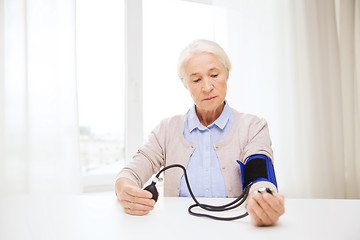 Image showing old woman with tonometer checking blood pressure