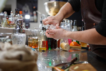 Image showing Bartender pours alcoholic drink into small glasses with flames